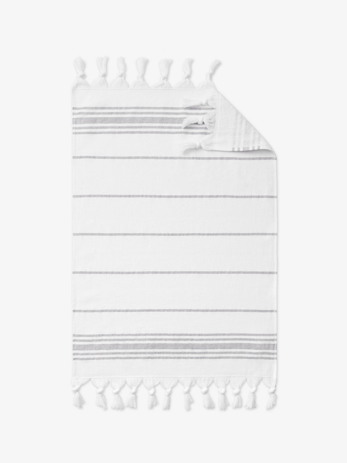 A gray and white striped Turkish cotton hand towel with white fringe laid out. 