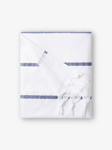A folded navy and white striped Turkish hand towel with white fringe.