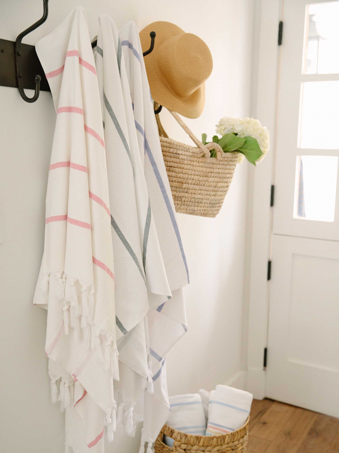 Three extra large striped Turkish towels—pink, charcoal, and navy—hanging side by side.