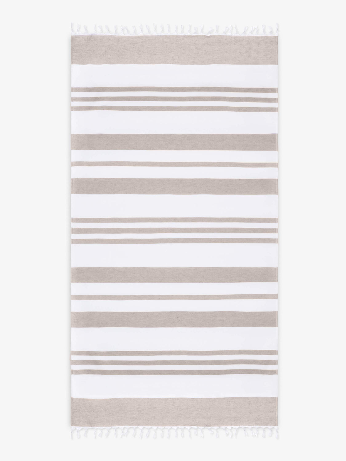 An oversized, tan and white striped Turkish cotton towel with white fringe laid out. 