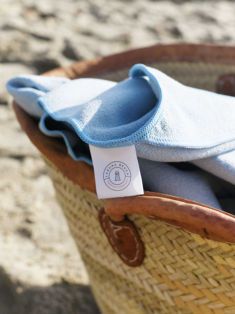 A close-up of a powder blue yoga mat towel in a decorative woven bag.