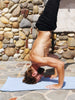 A man doing a headstand on a powder blue yoga mat towel.