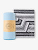 A rolled up powder blue yoga mat towel and a folded noir Mexican blanket.