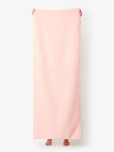 A blush colored yoga mat towel being held up by a person.