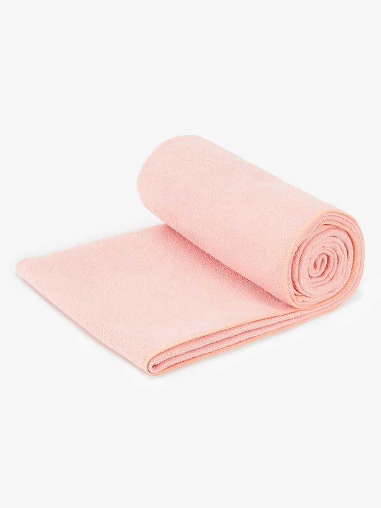 A blush colored yoga mat rolled up.