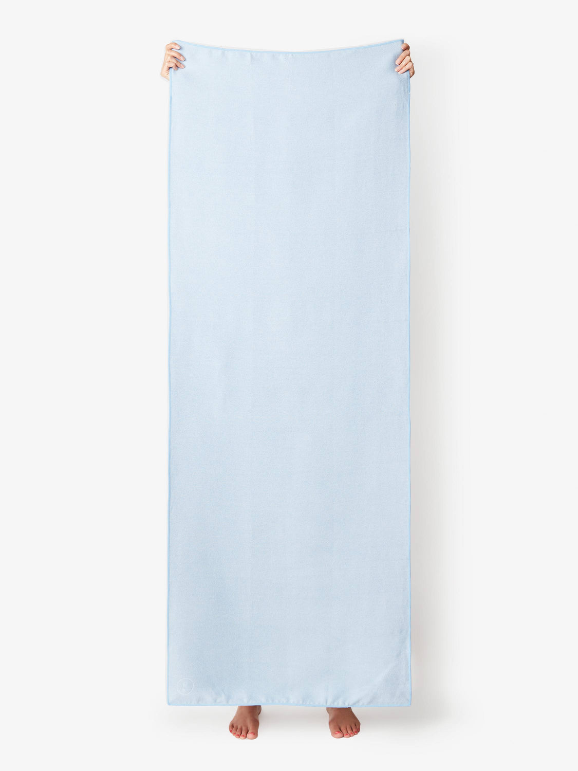 A powder blue yoga mat towel being held up by a person.